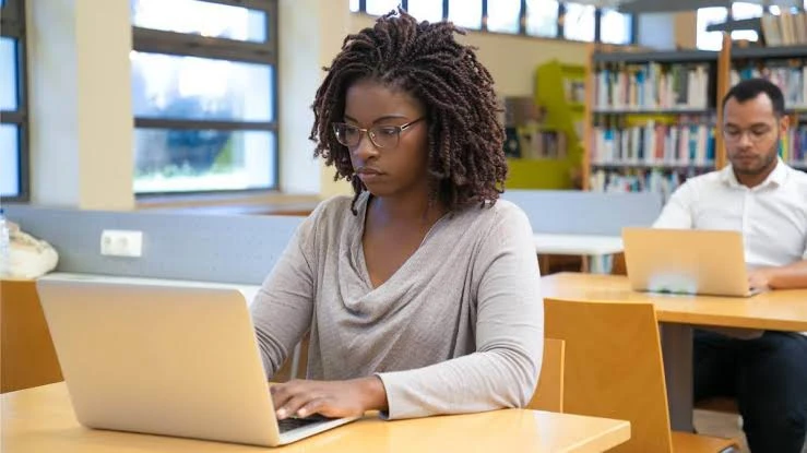 Kingdom Foundation College student studying on a laptop in the library