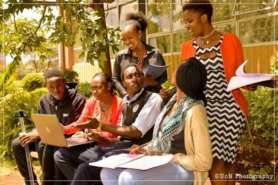 Kingdom Foundation College students discussing coursework around a laptop